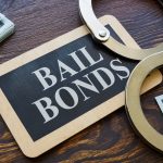 Bail bonds sign with handcuffs and cash on a wooden desk